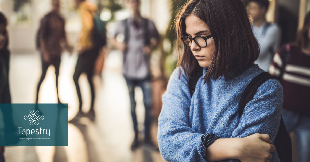 Young girl appearing to be upset with wrapping her arms around herself