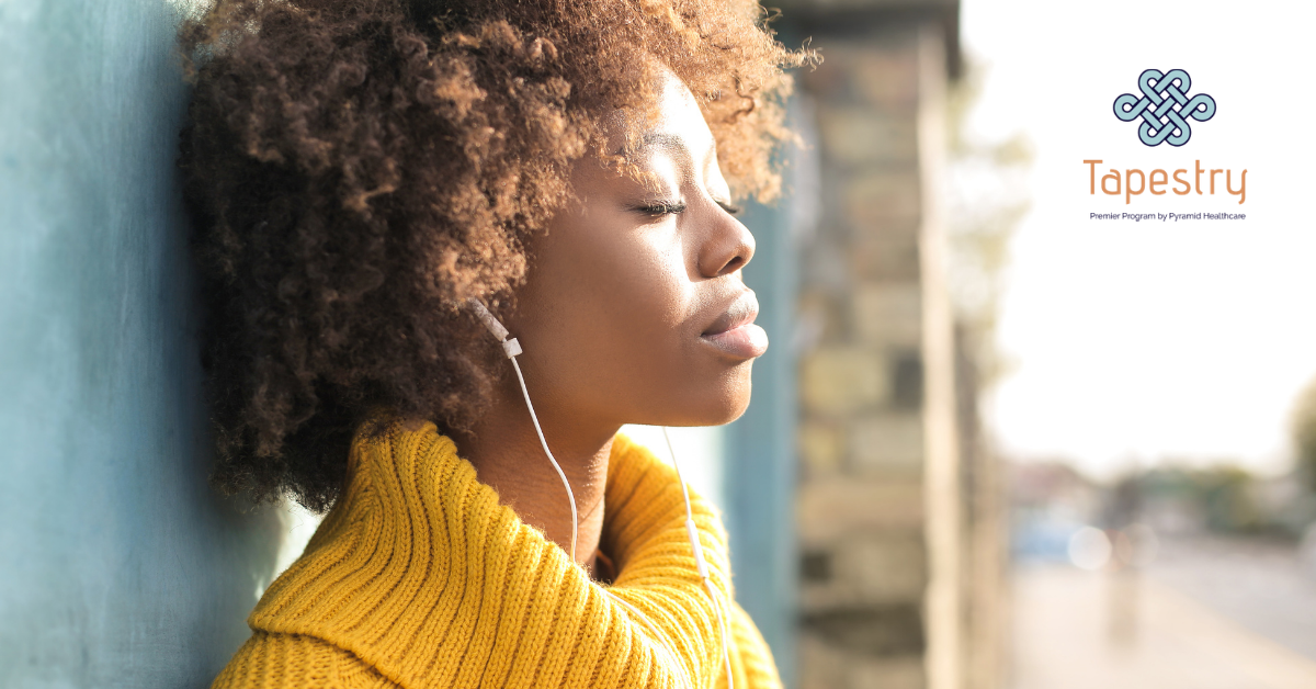 African American woman listening to music with her eyes closed while standing outside