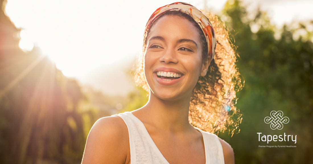 Young adult African American woman smiling while the sun shines behind her