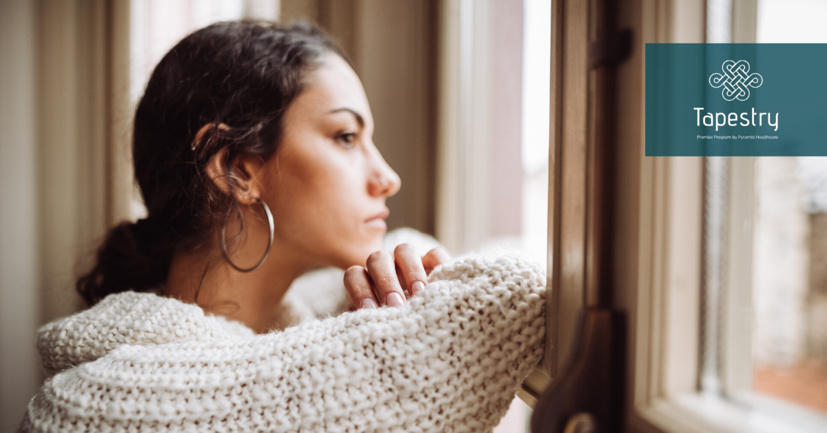 Young adult woman looking out the window, seems to be depressed