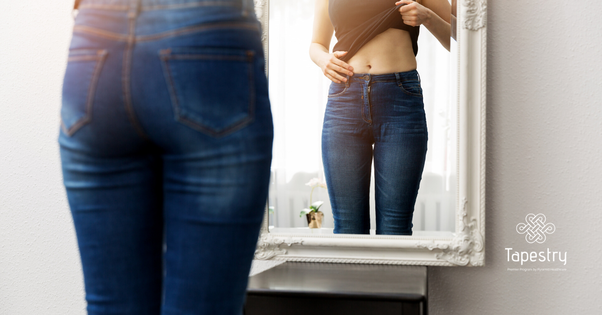 Woman looking at her stomach in the mirror