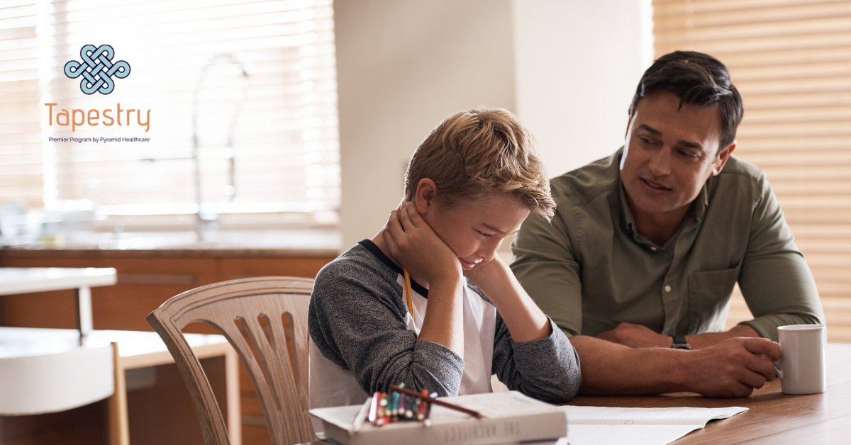 Father helping his son out with homework at the kitchen table