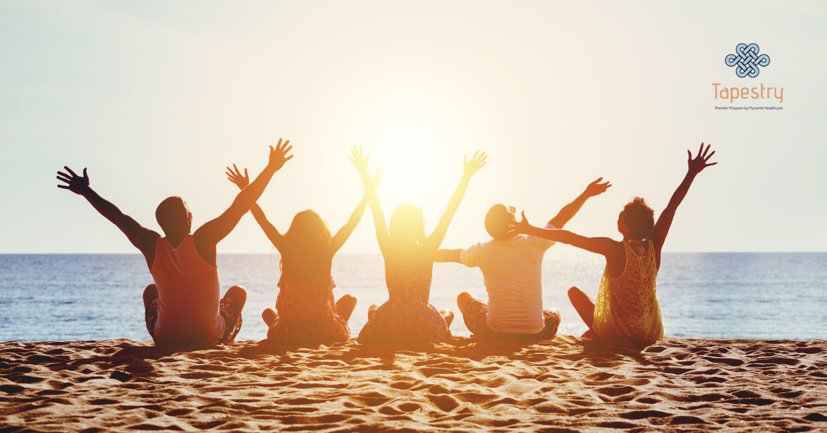 Group of friends sitting on the beach with their arms in the air