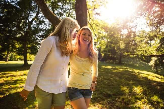 Mother and daughter walking through the park, smiling