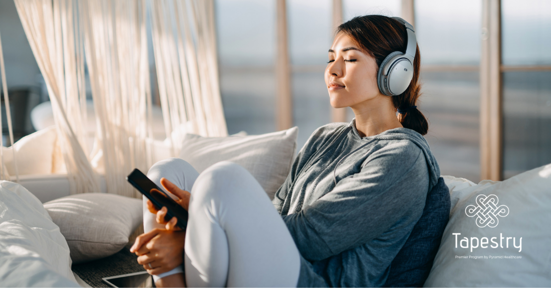 Woman sitting on her couch listening to a podcast/music on her phone