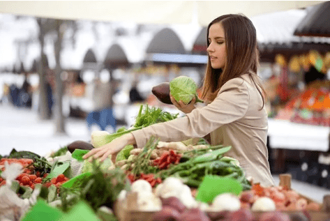 Young adult woman buying vegetables from a farm market