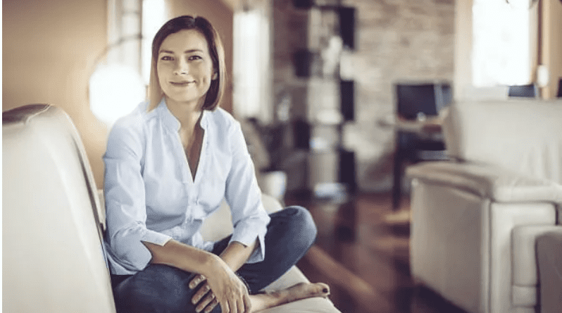 Young adult woman sitting on a couch in her apartment