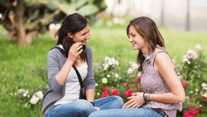 Two female friends having a conversation in a field of flowers