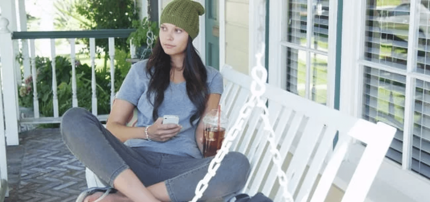 Woman sitting on her front porch with a soft drink in her hand
