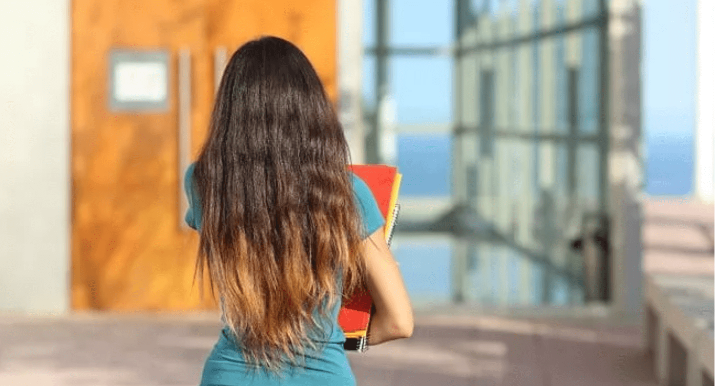 Teenage girl walking towards school with her books in her hand