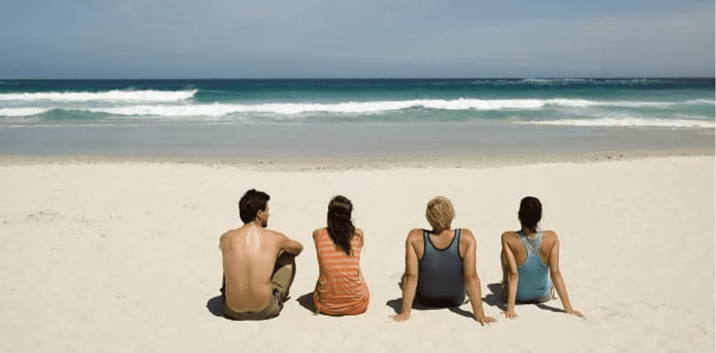 Family sitting on the beach looking out at the ocean