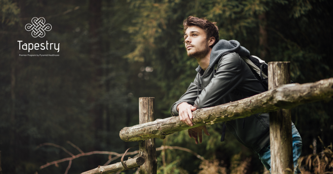 Young adult man hiking, stopped to take a break and look out over the area