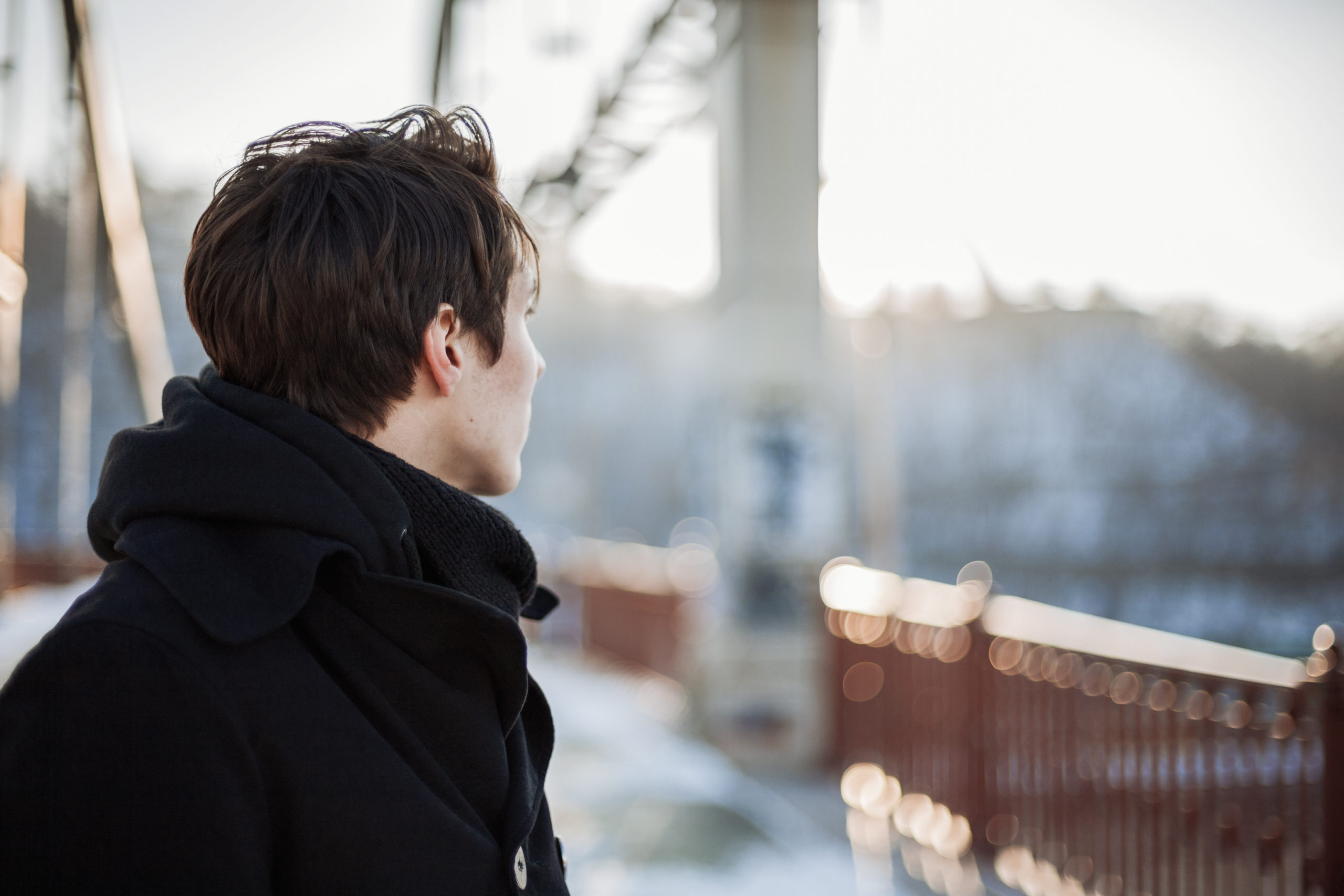 Hipster guy standing on the bridge looking away