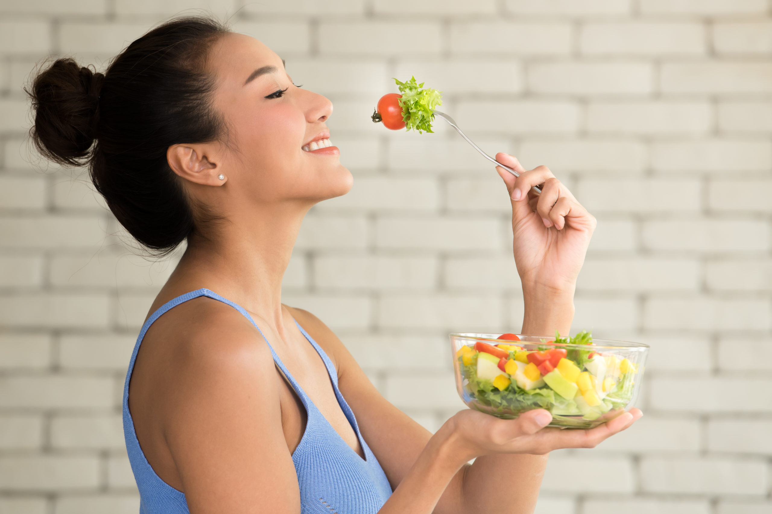 Asian woman in joyful postures with hand holding salad bowl