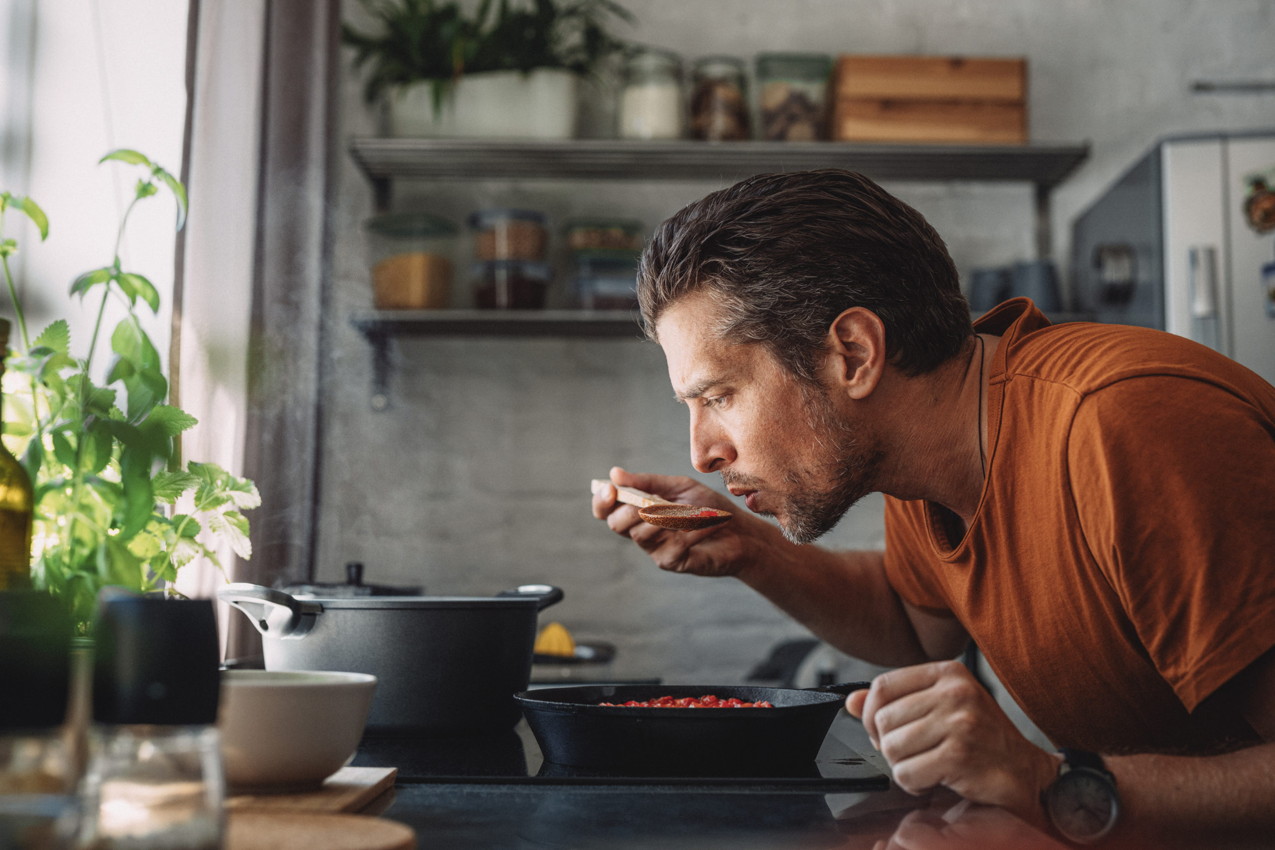 Young man tasting sauce with a mixing spoon