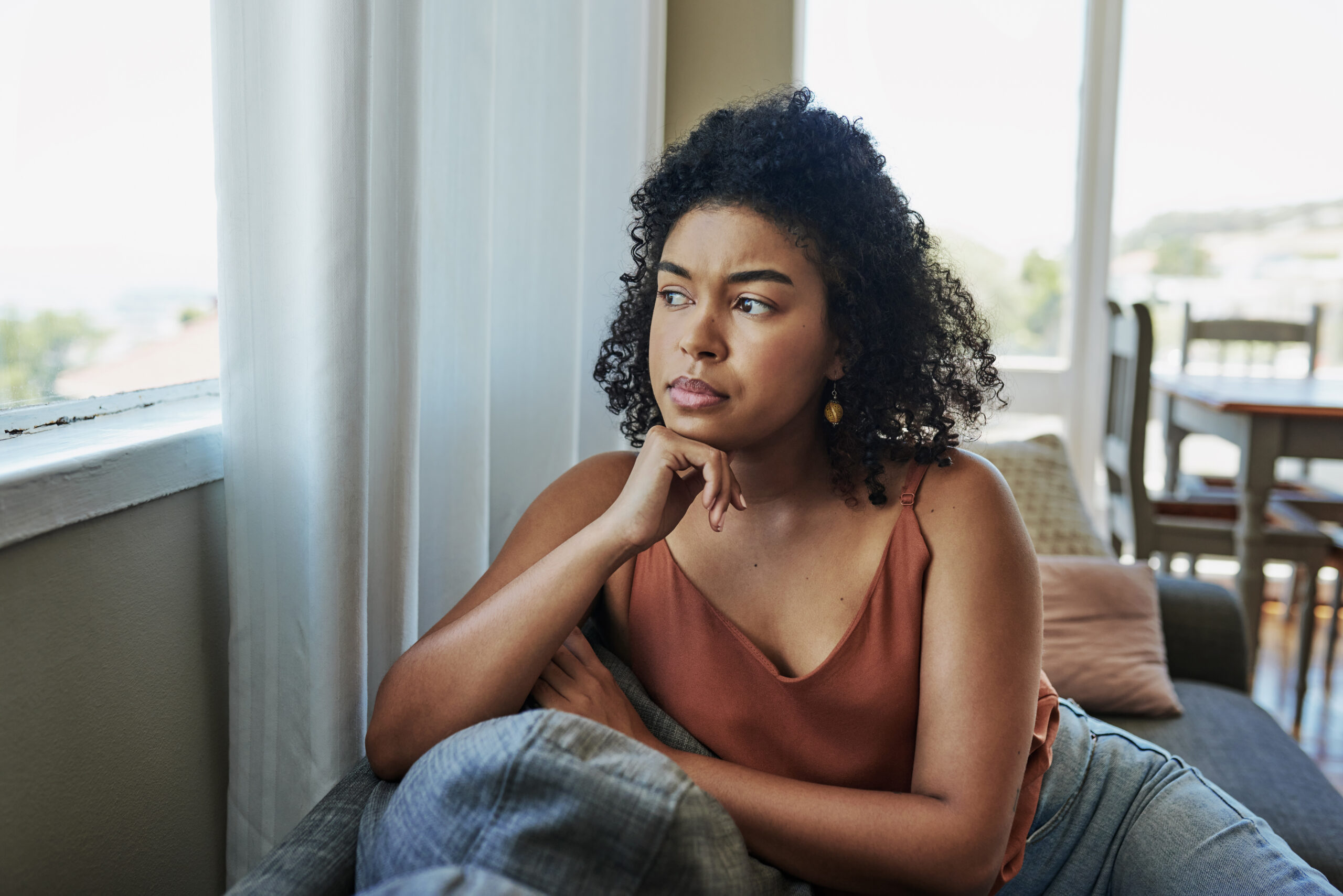 Young woman looking pensively out the window at home