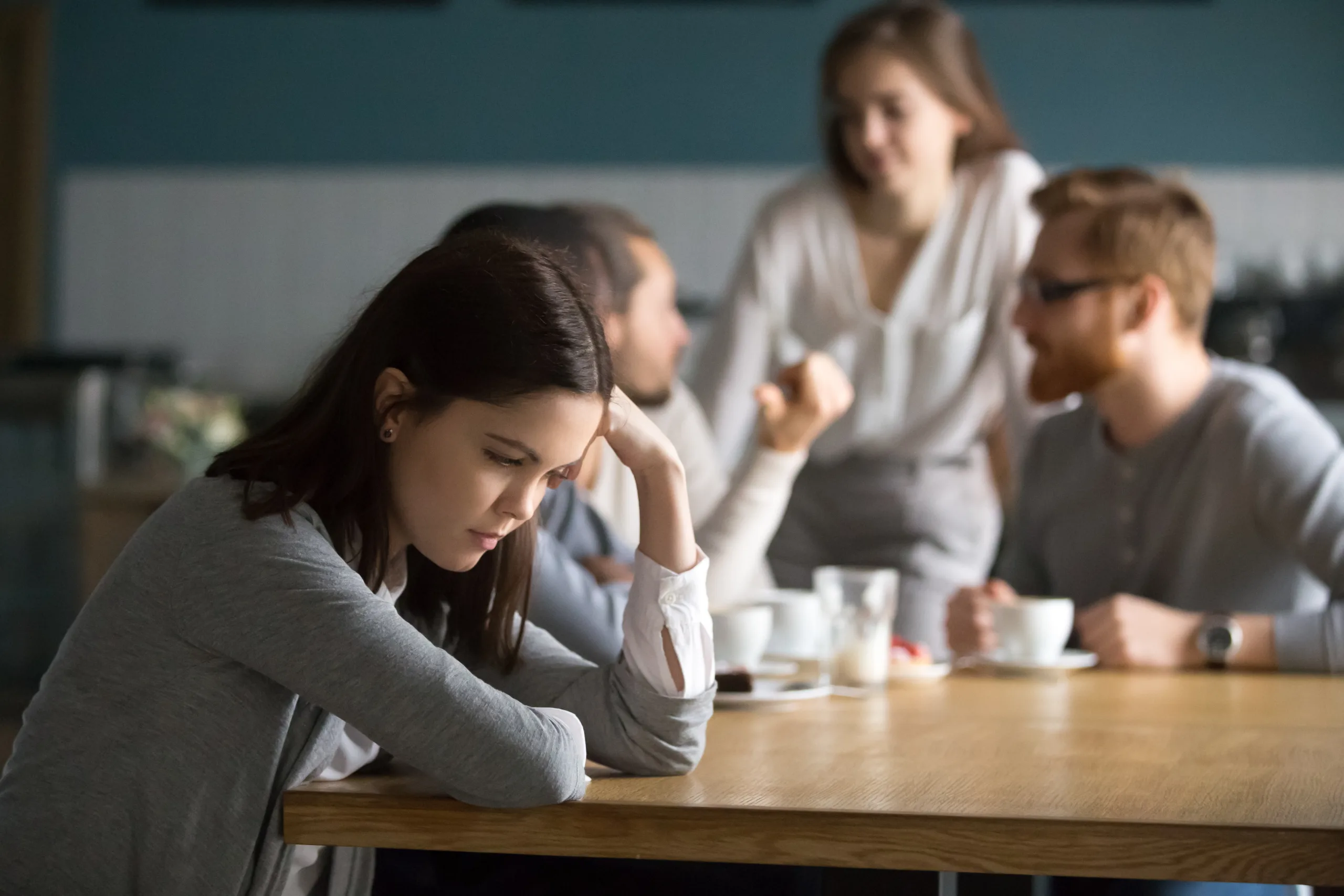 Upset young girl sit alone at coffee table in cafÃ© feeling lonely or offended, sad female loner avoid talking to people, student outsider suffer from discrimination, lacking friends or company