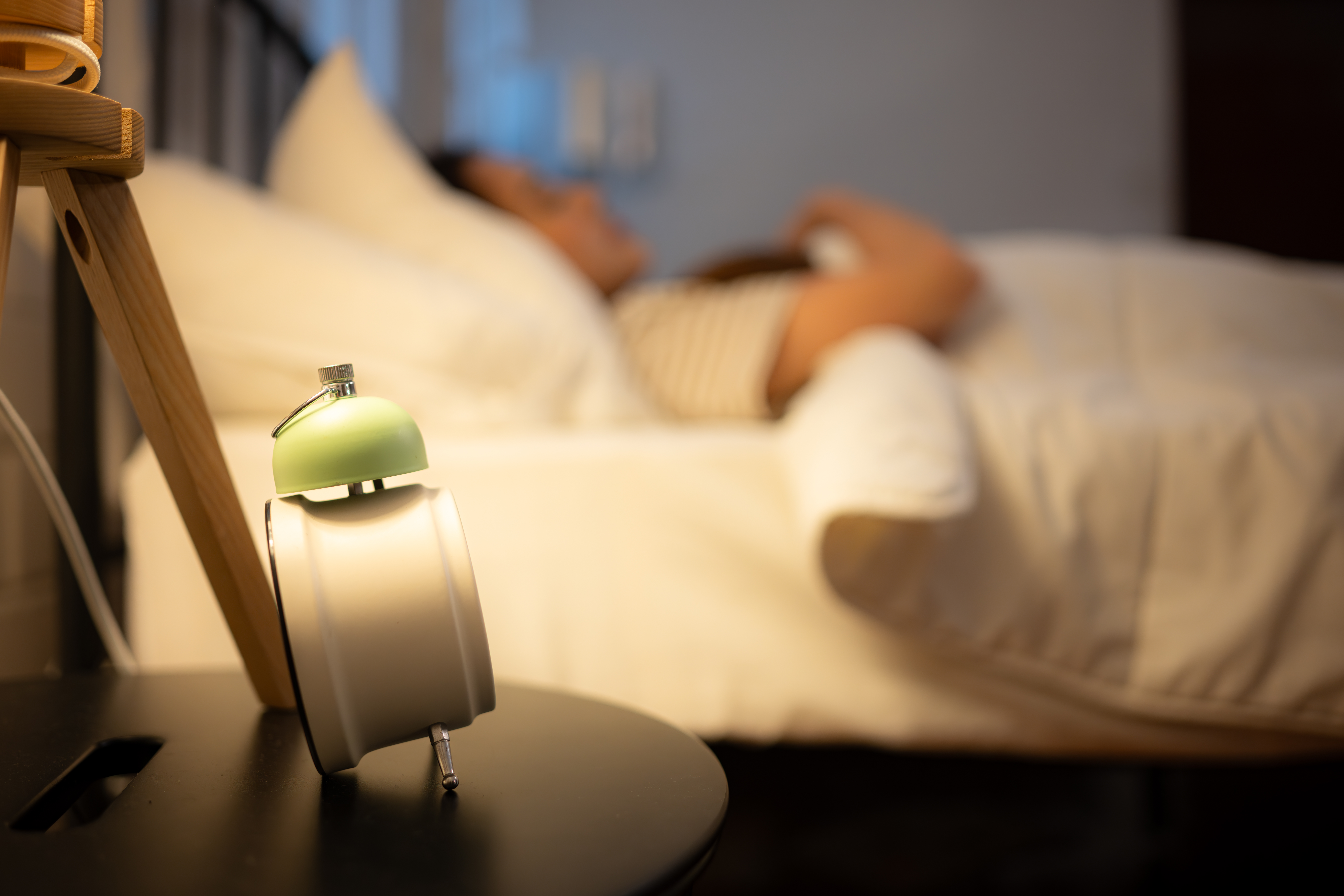 Alarm clock on a bedside table with woman sleeping in the background after taking ambien